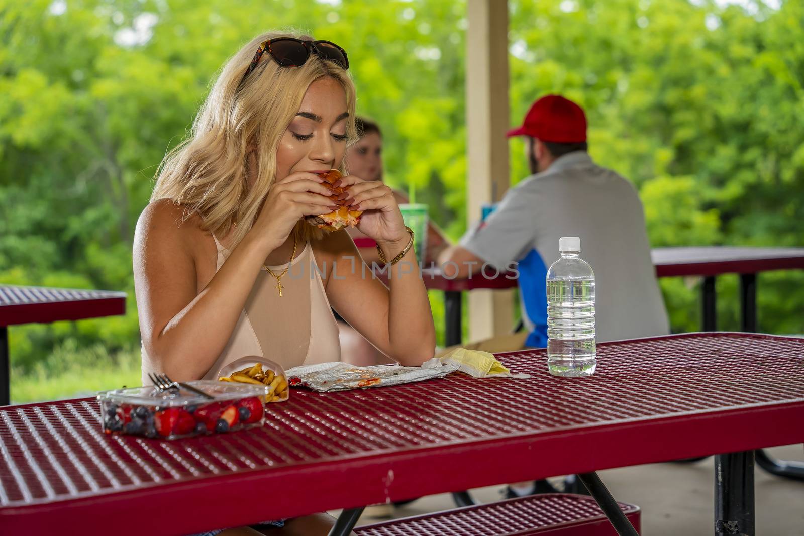 A gorgeous young blonde model enjoys her lunch outdoors while maintaining a safe distance from others during the Covid-19 pandemic