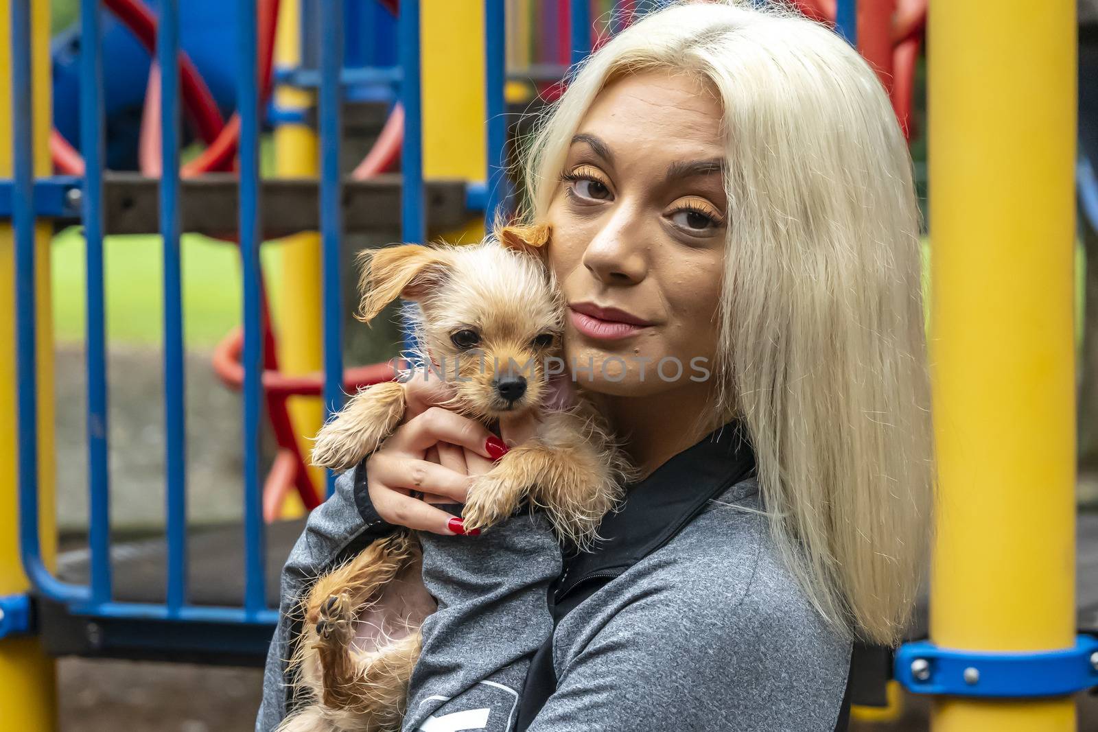 A gorgeous young blonde model poses outdoors with her young puppy