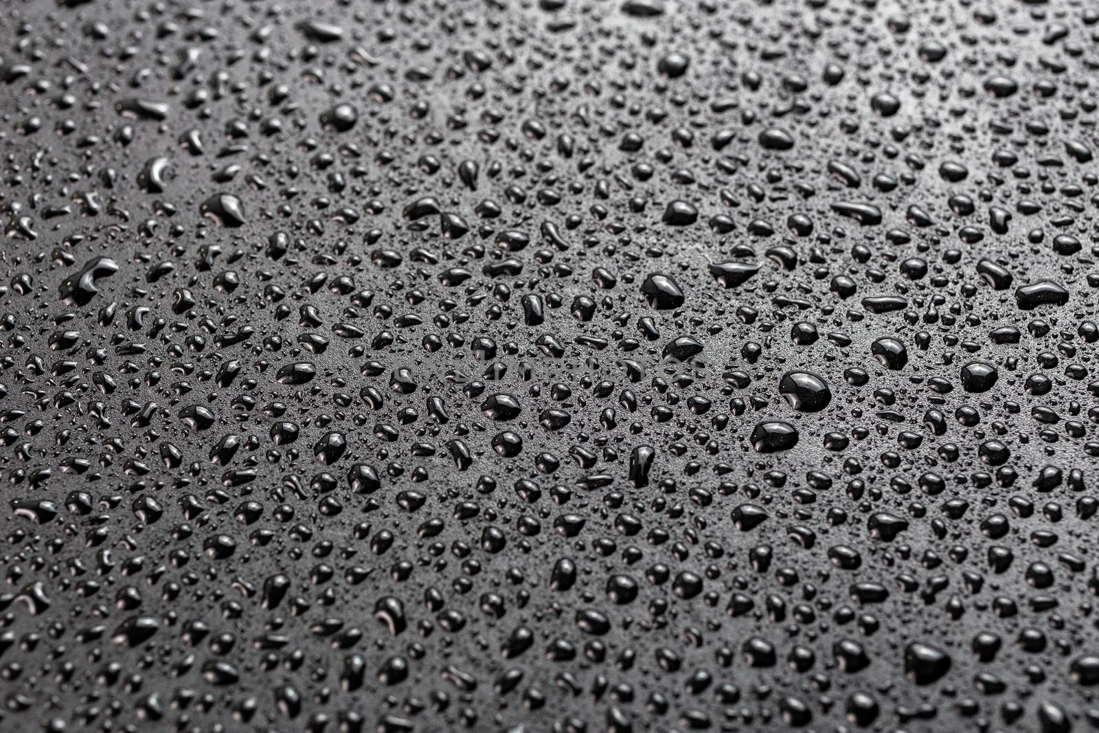 water drops on abstract flat black hydrophobic surface macro background with selective focus and blur