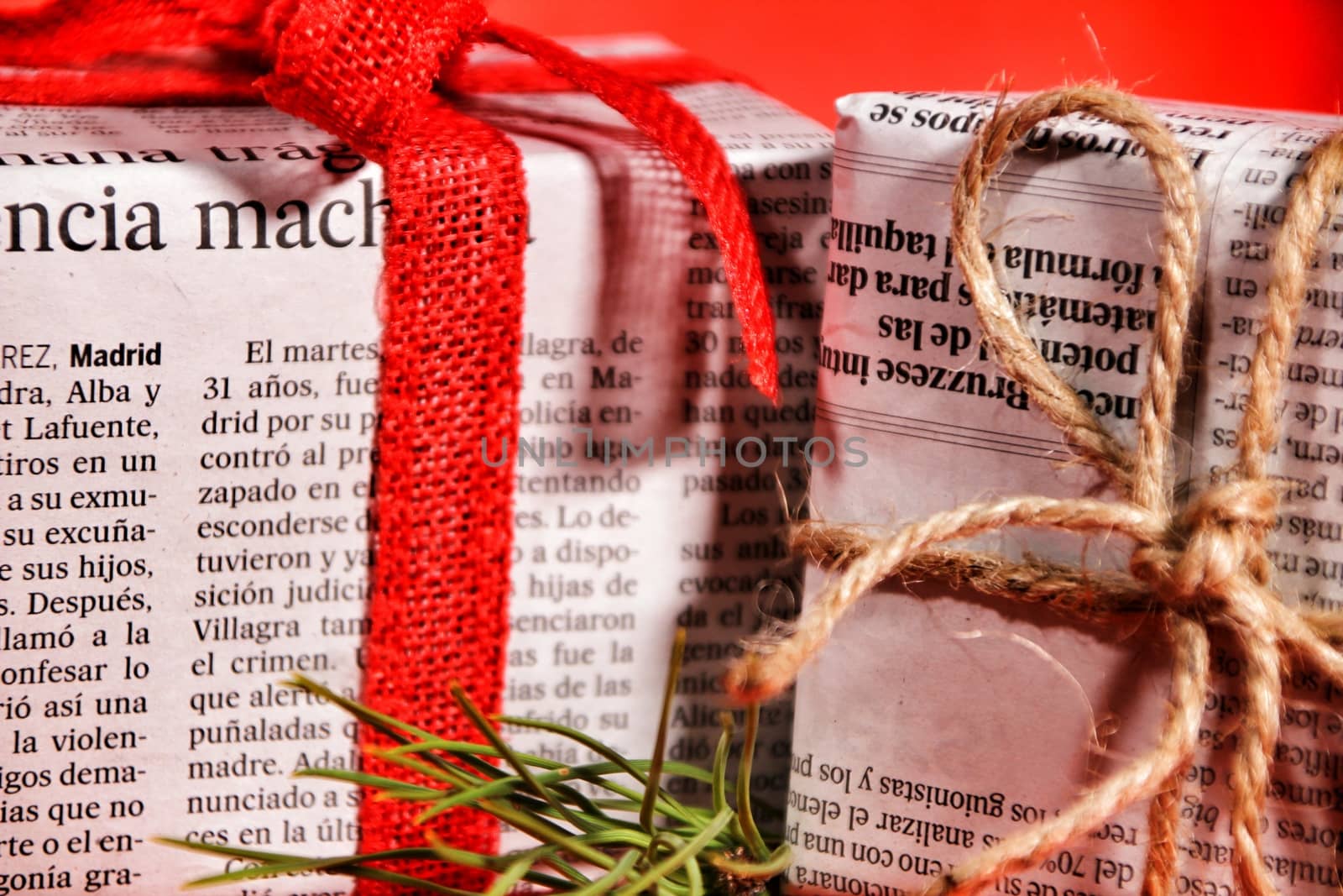 Gifts wrapped in old newspaper on red background by soniabonet