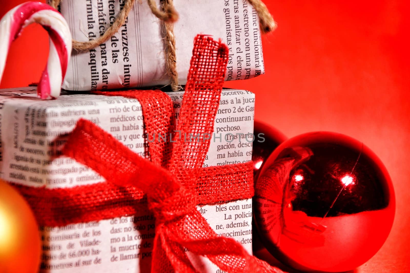 Gifts wrapped in old newspaper with red bow and rope on red background