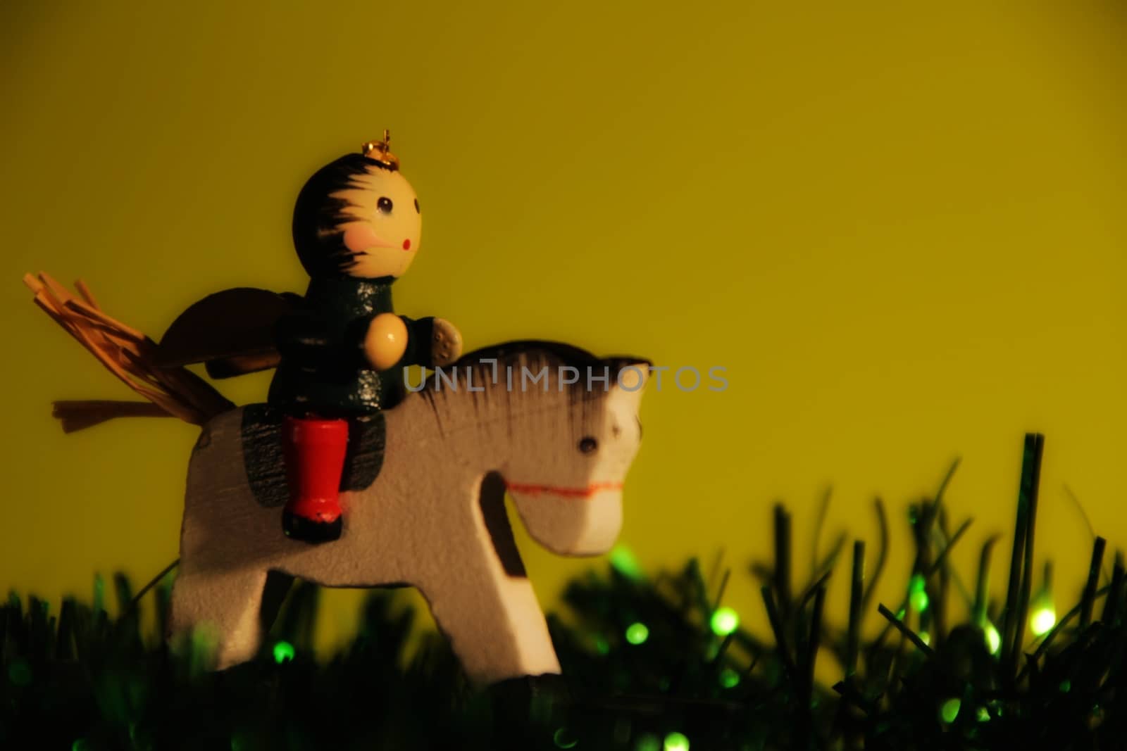 Beautiful Angel Christmas ornament ridding a horse with green garland. Light Green background