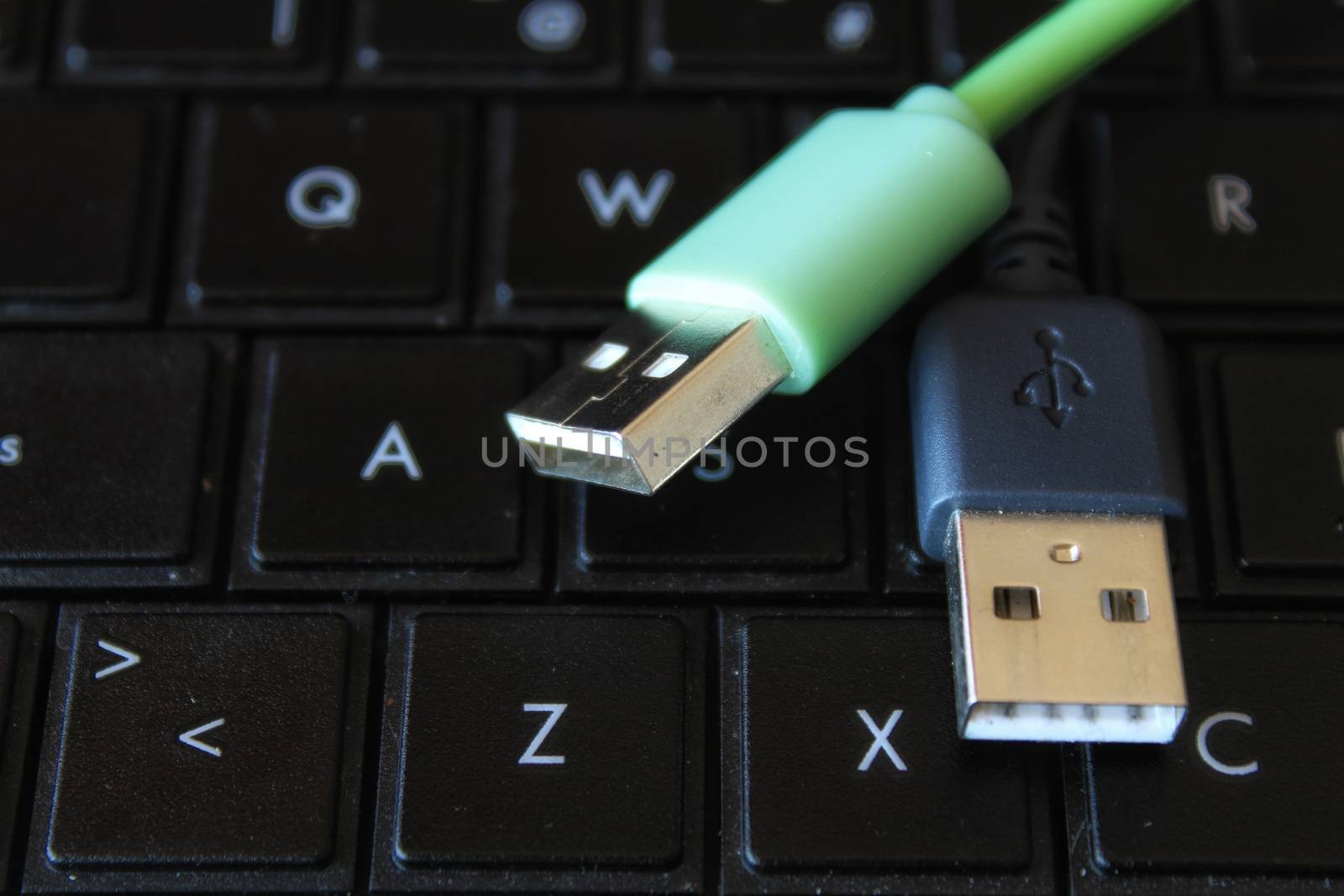 Black and green USB connectors on black keyboard laptop