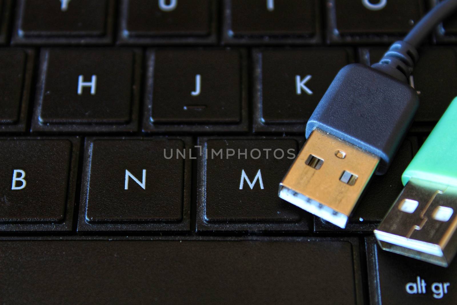 Black and green USB connectors on black keyboard laptop