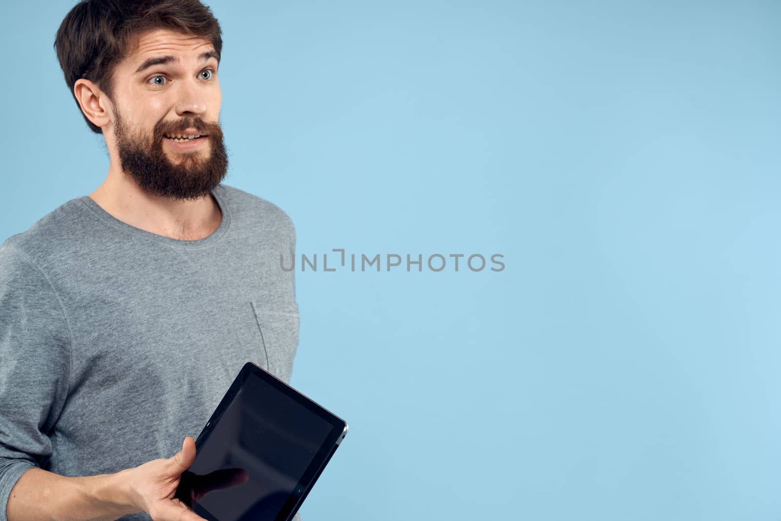 Man holding tablet in hands wireless technology internet lifestyle studio blue background emotions. High quality photo