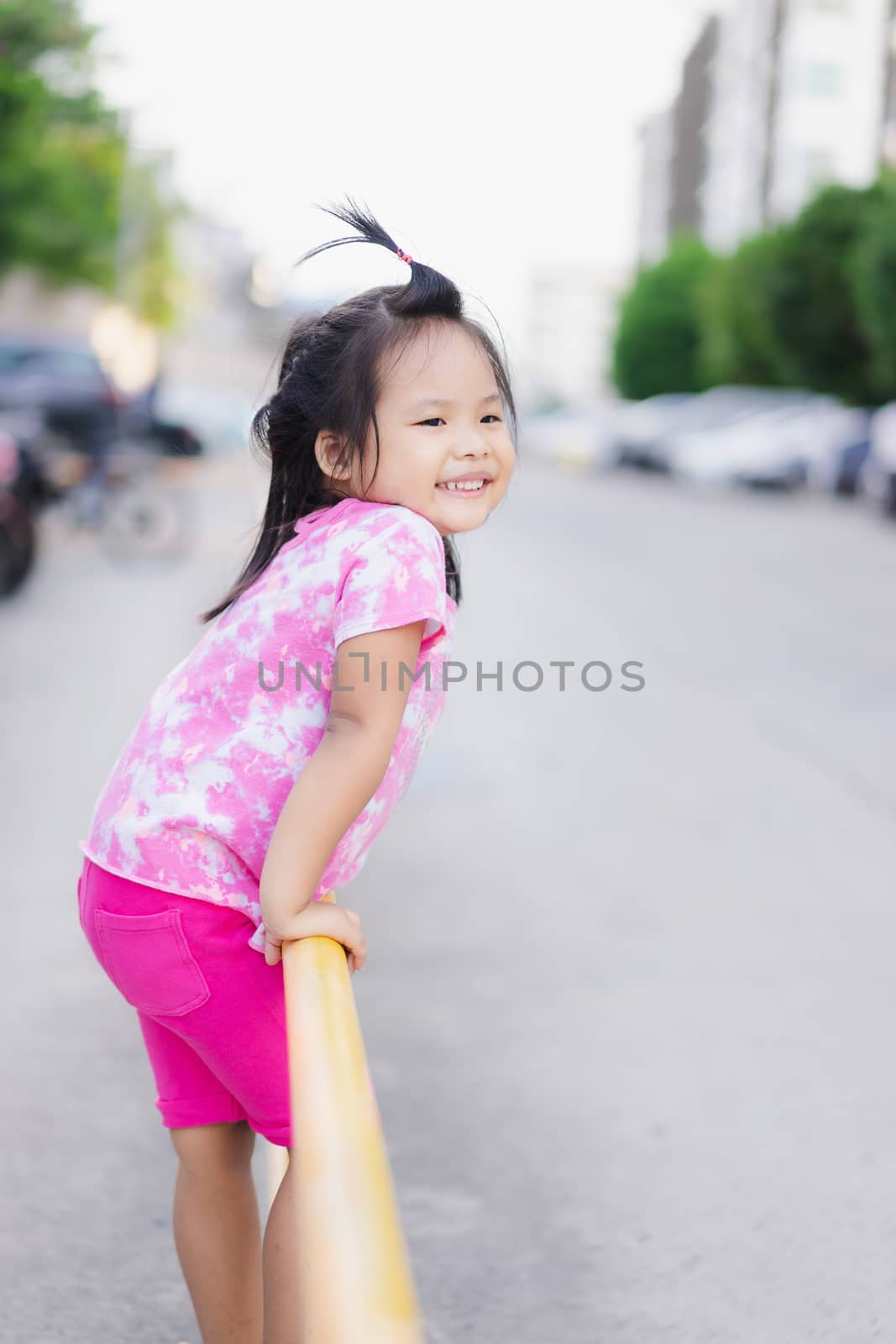Little girl climbing yellow fence in the park by domonite