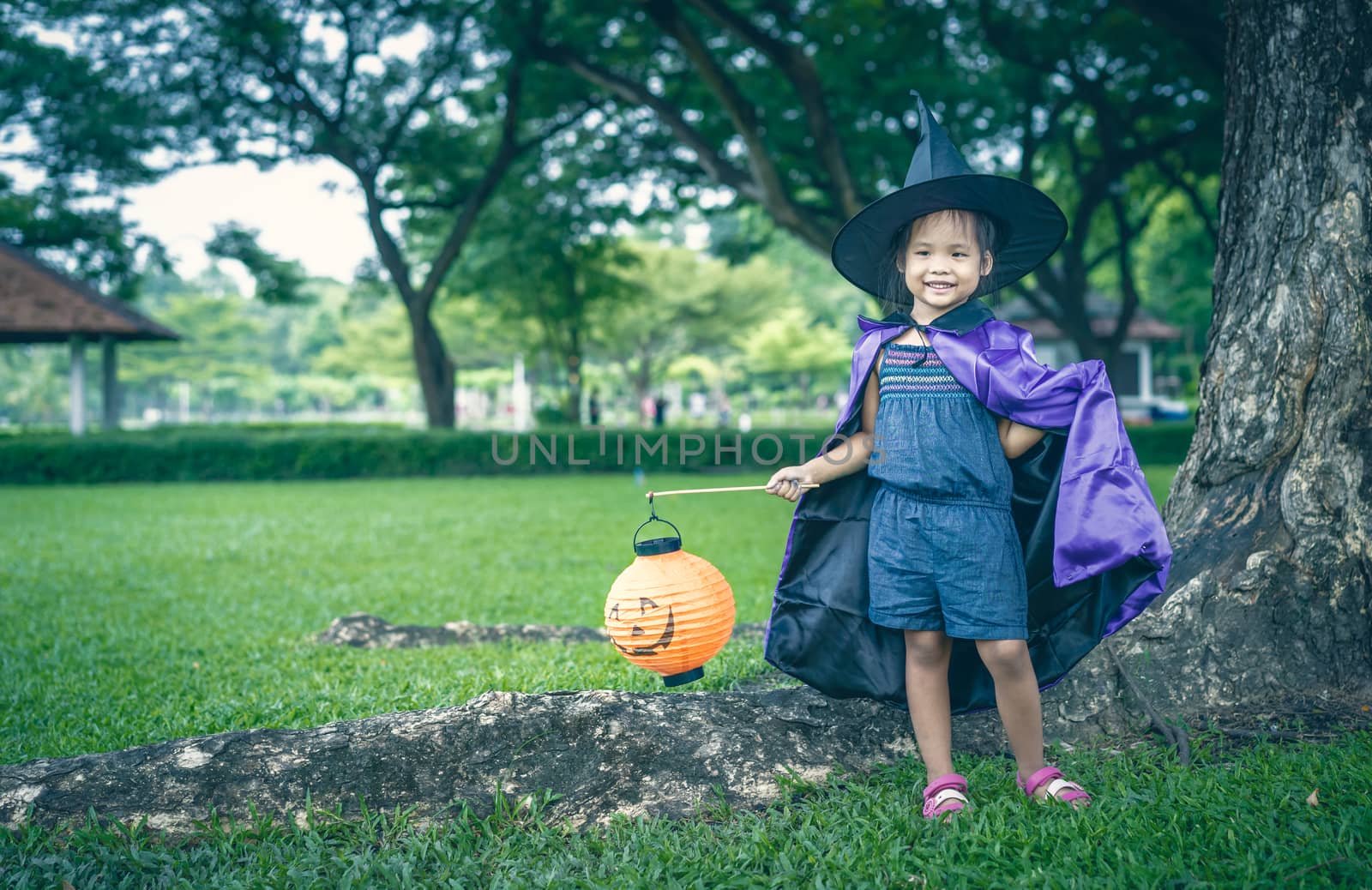 Little girl in a witch costume holding a lamp in halloween