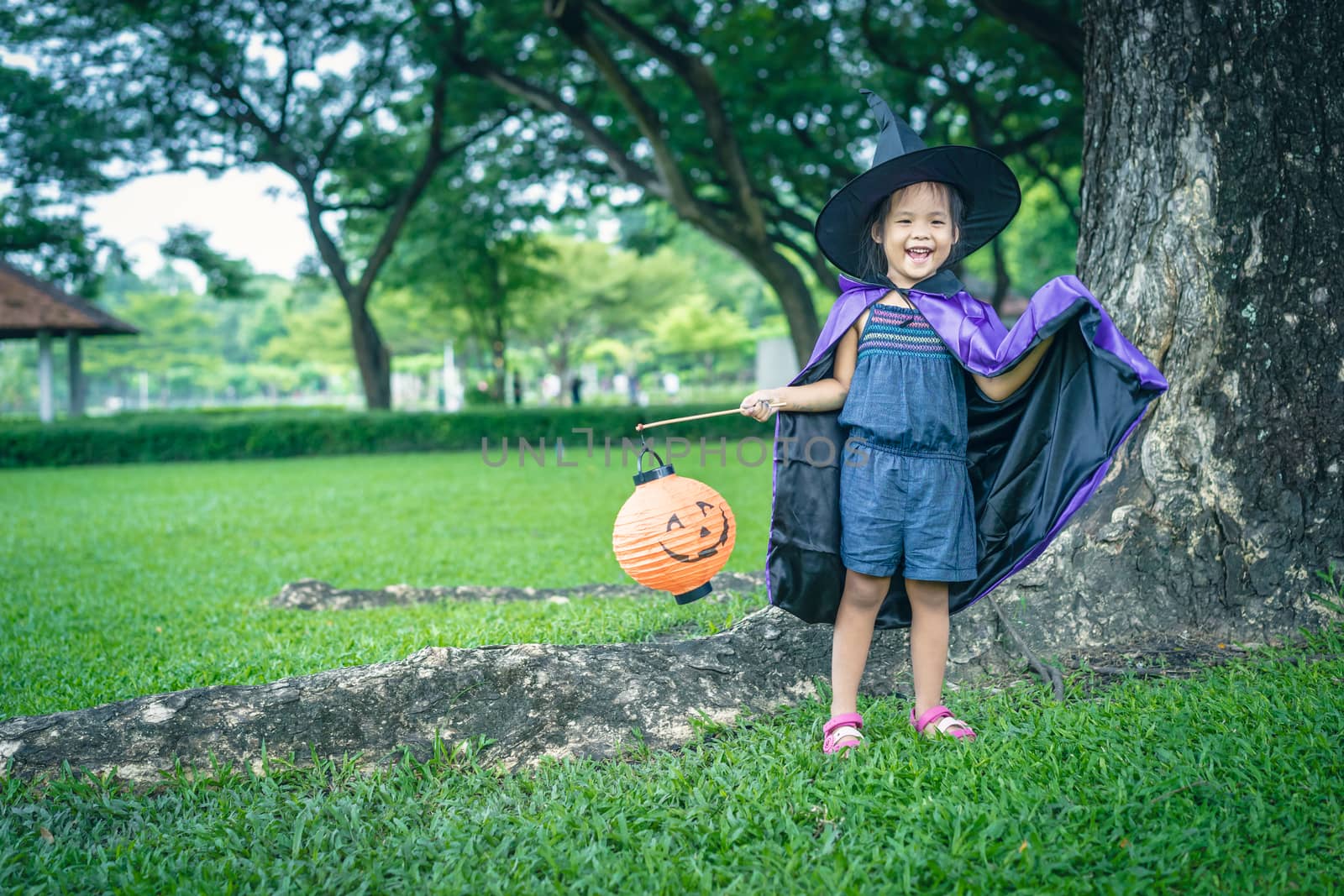 Little girl in a witch costume holding a lamp in halloween