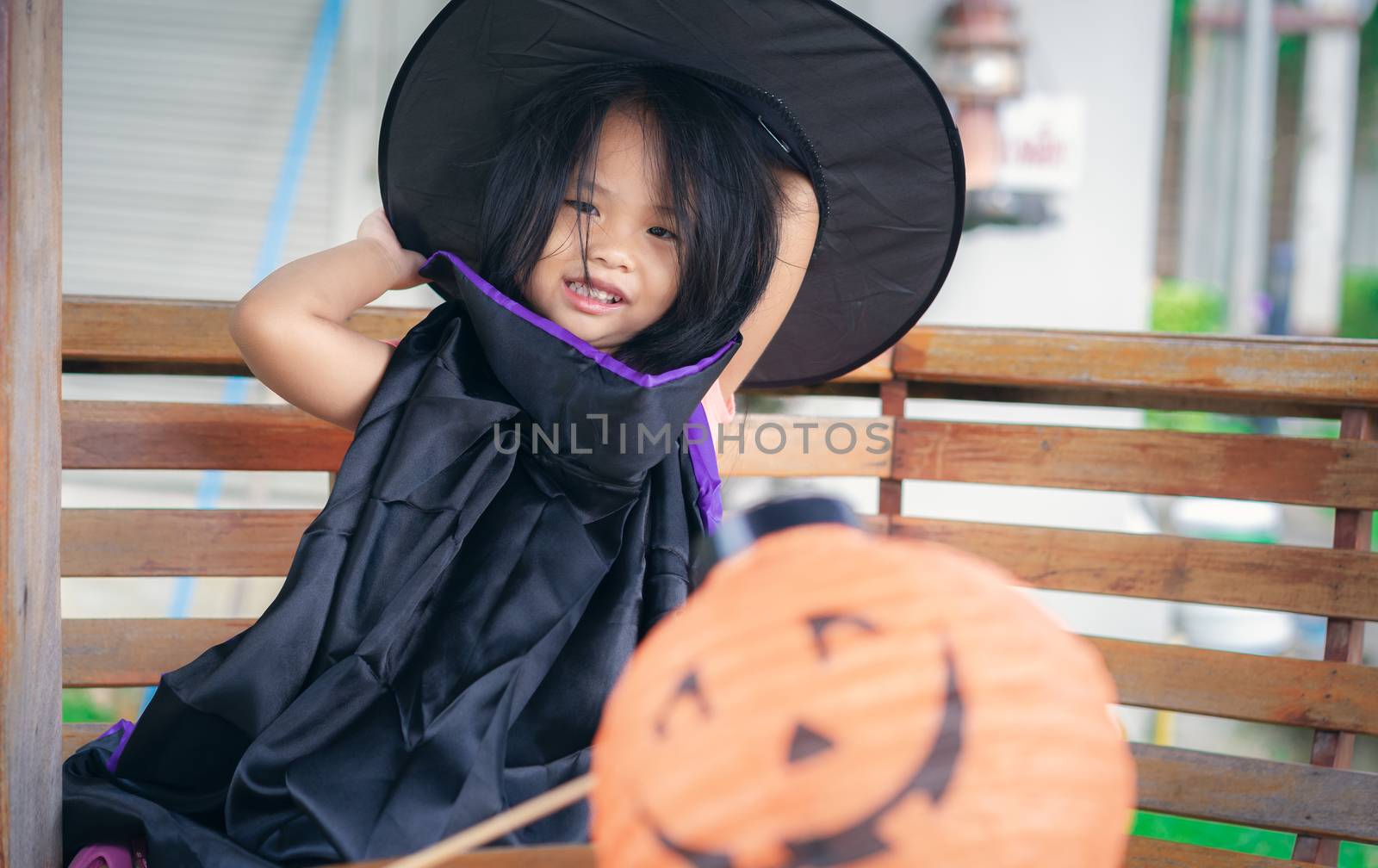 Little girl in a witch costume and lamp in halloween