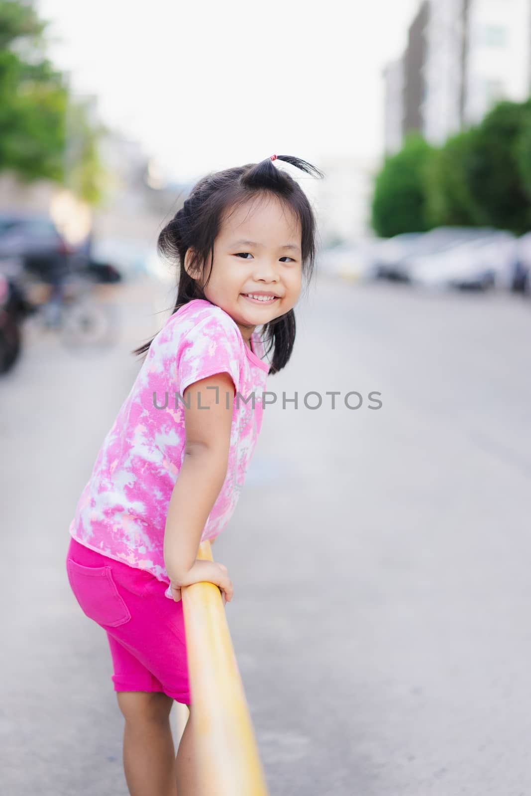 Little girl climbing yellow fence in the park by domonite