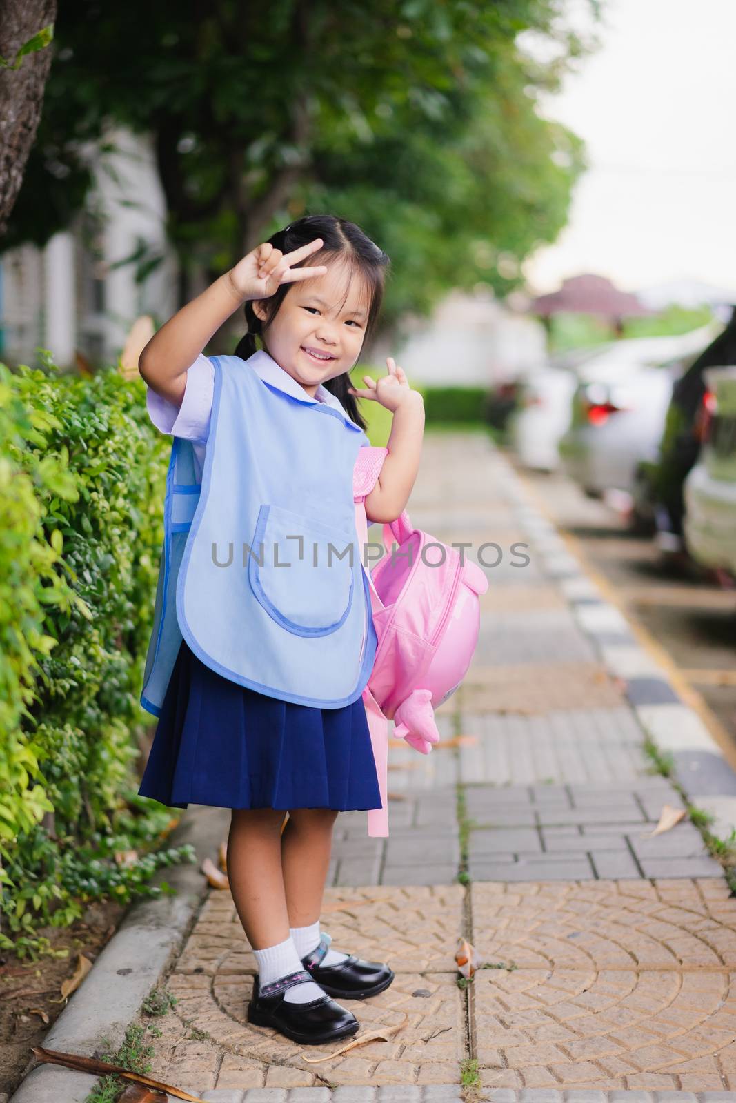happy little girl in Thai school uniform with backpack standing in the park , ready back to school