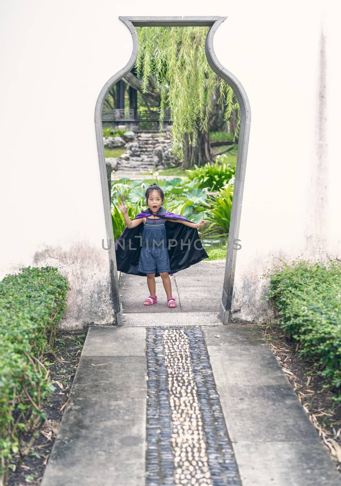 Little girl in a witch costume standing at the door in halloween by domonite