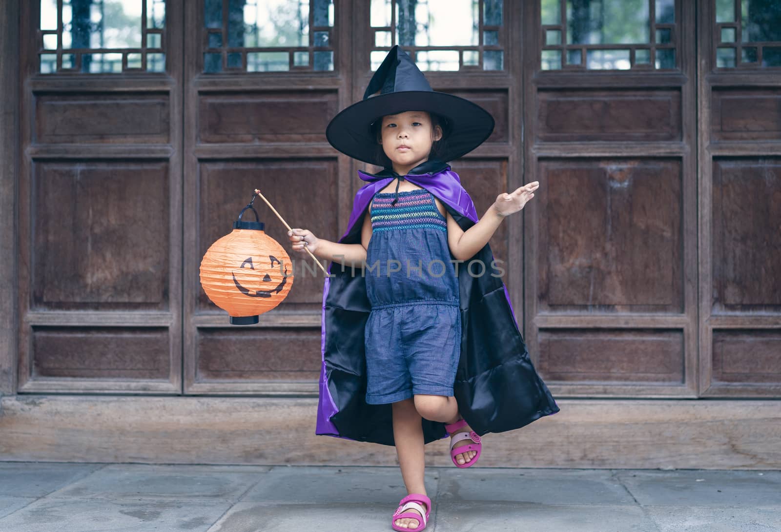 Little girl in a witch costume holding a lamp in halloween