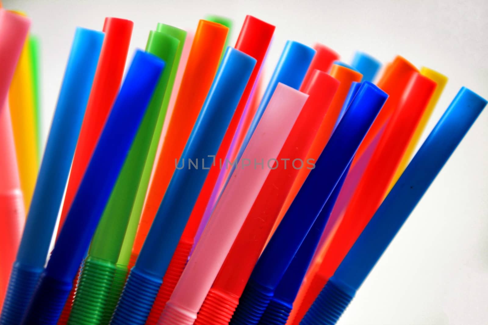 Colorful plastic drinking straws close up white background