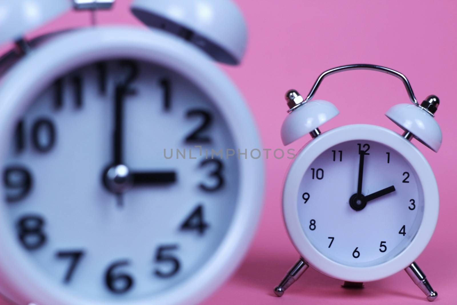Clock marking winter time change in autumn pink background