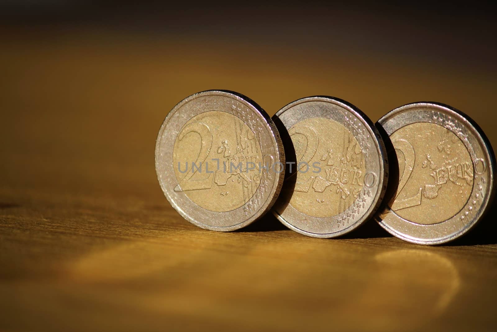 Two euro coins on brown wooden board