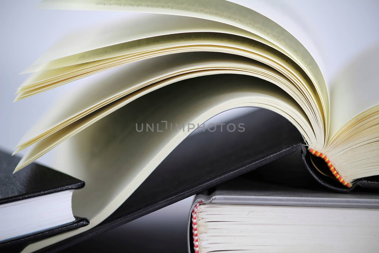 Black and white books stacked on white background one of them opened