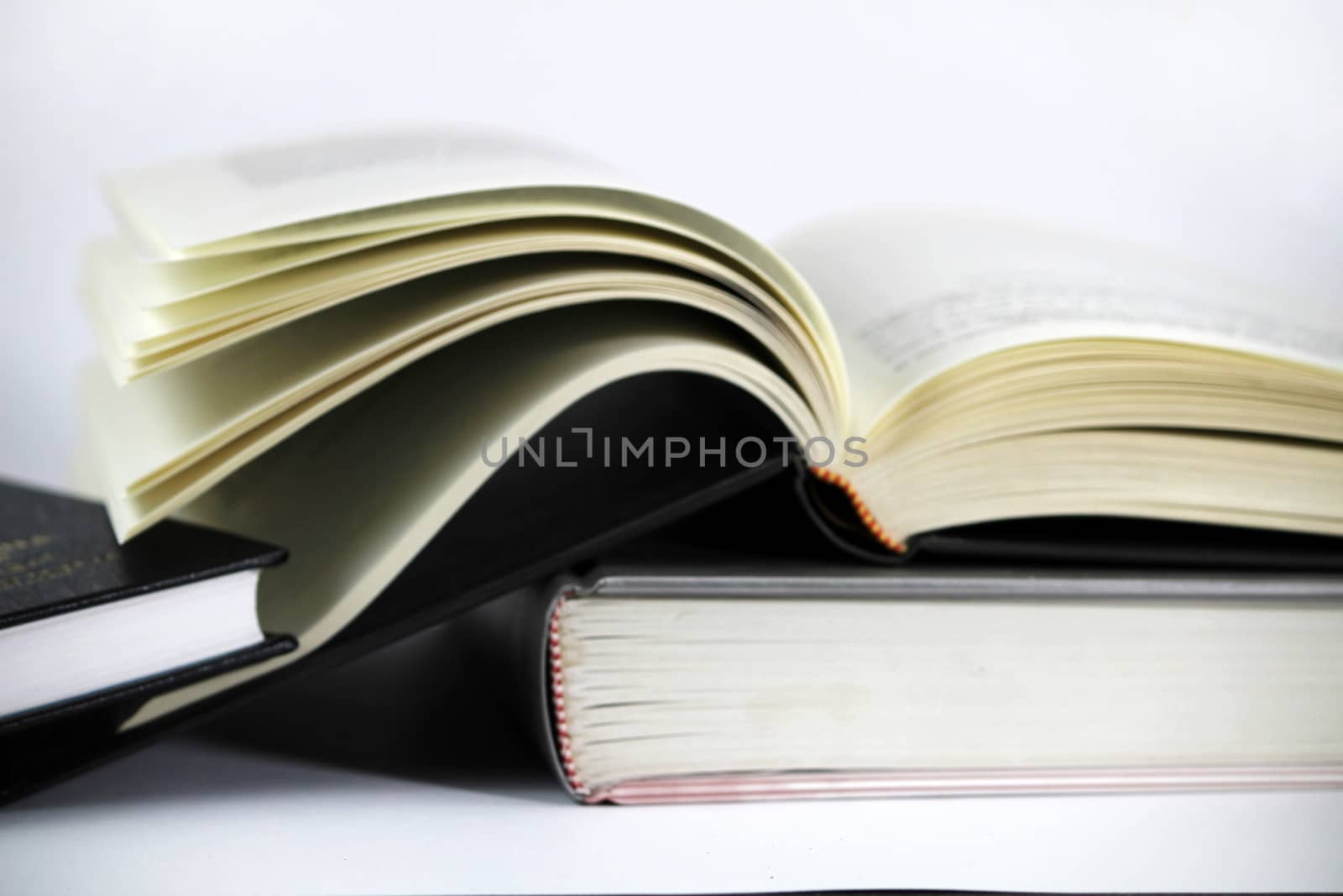 Black and white books stacked on white background one of them opened