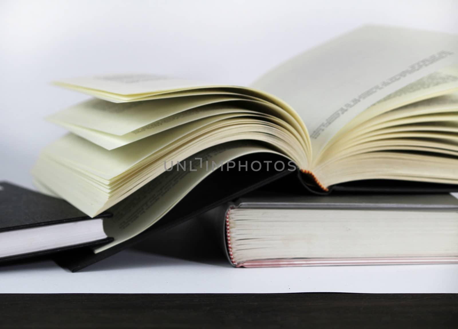 Black and white books stacked on white background one of them opened