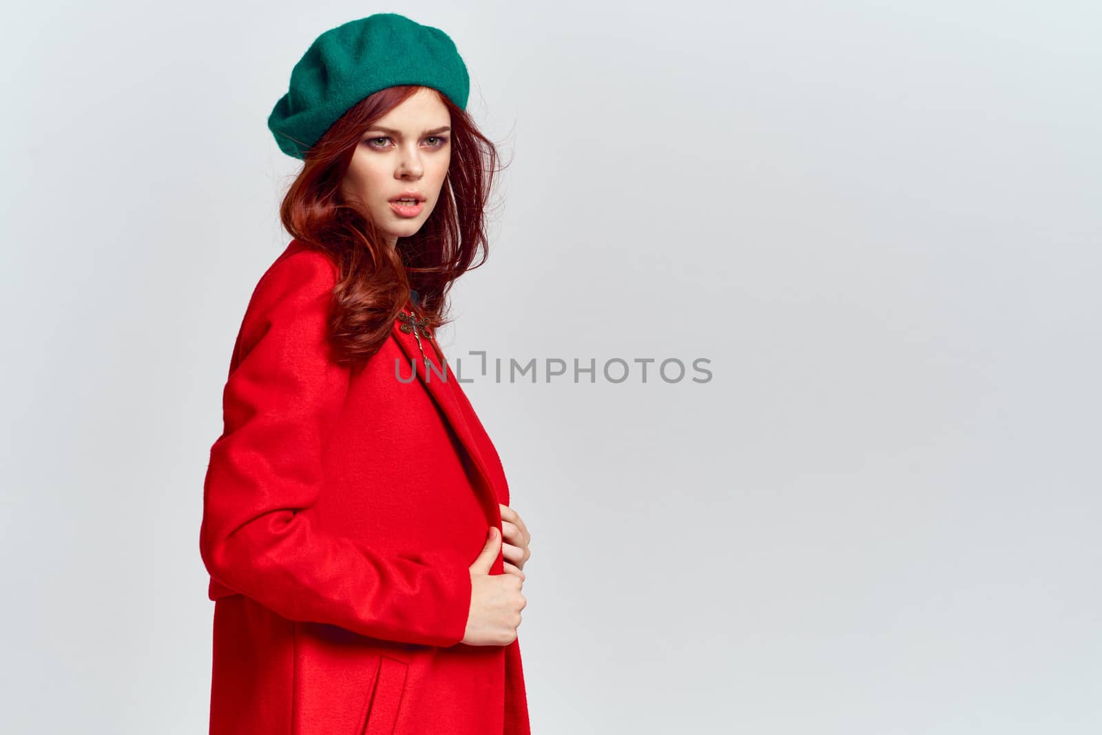 Woman in red coat and in green hat on isolated background cropped model with Copy Space emotions. High quality photo