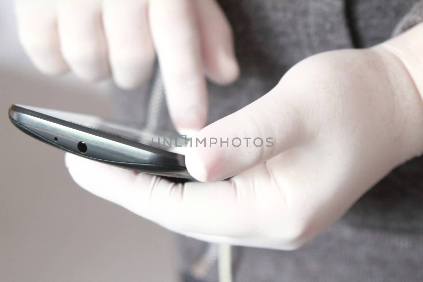 Hands in white latex surgical gloves holding a mobile phone