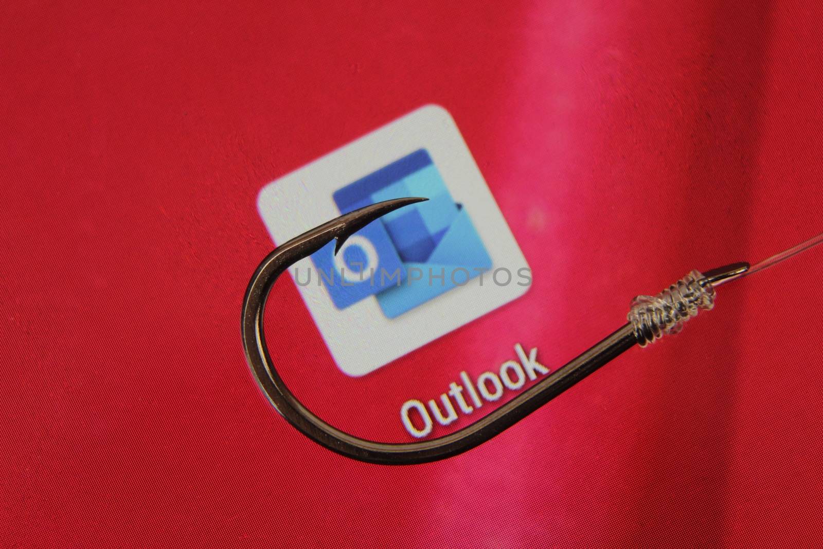 Madrid, Spain- May 10, 2010: Conceptual picture emulating phishing scam with a hook on Outlook icon on red screen