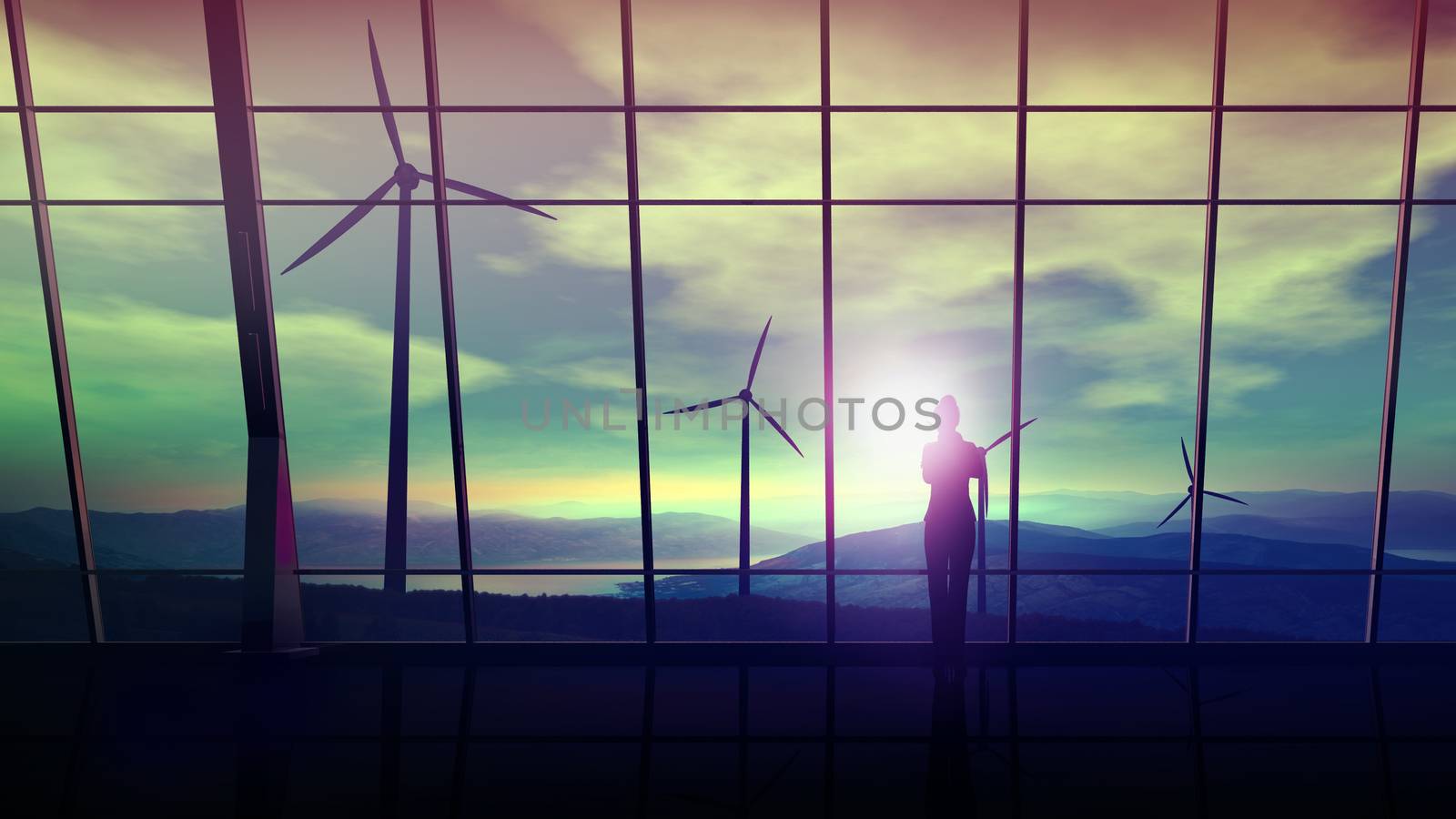 A silhouette of a business woman is standing against an office window overlooking the wind turbines.