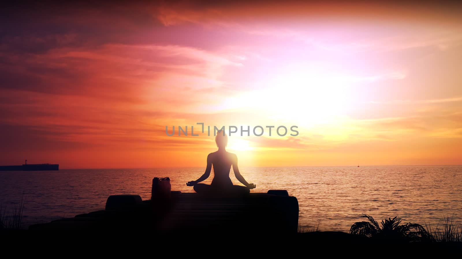 Silhouette of a woman meditating against a sunset in the ocean.