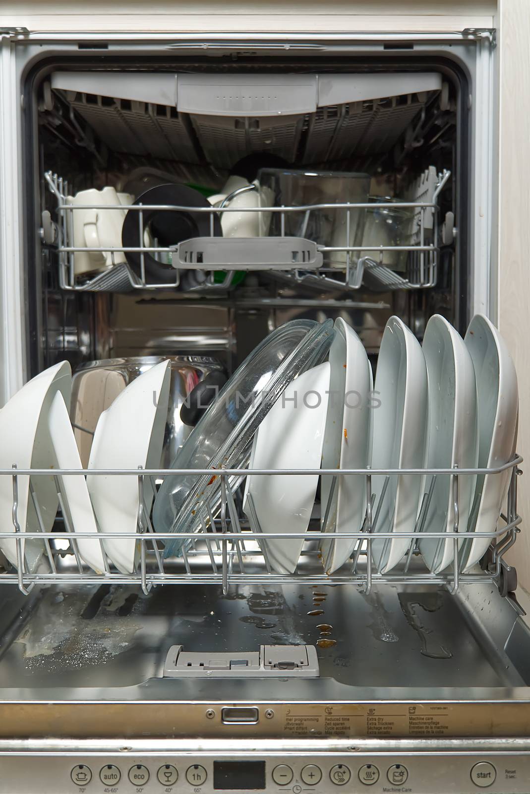 Dirty dish in open integrated dishwasher. full loaded dishwasher ready for washing. Open dishwasher with dirty dishes inside before washing.
