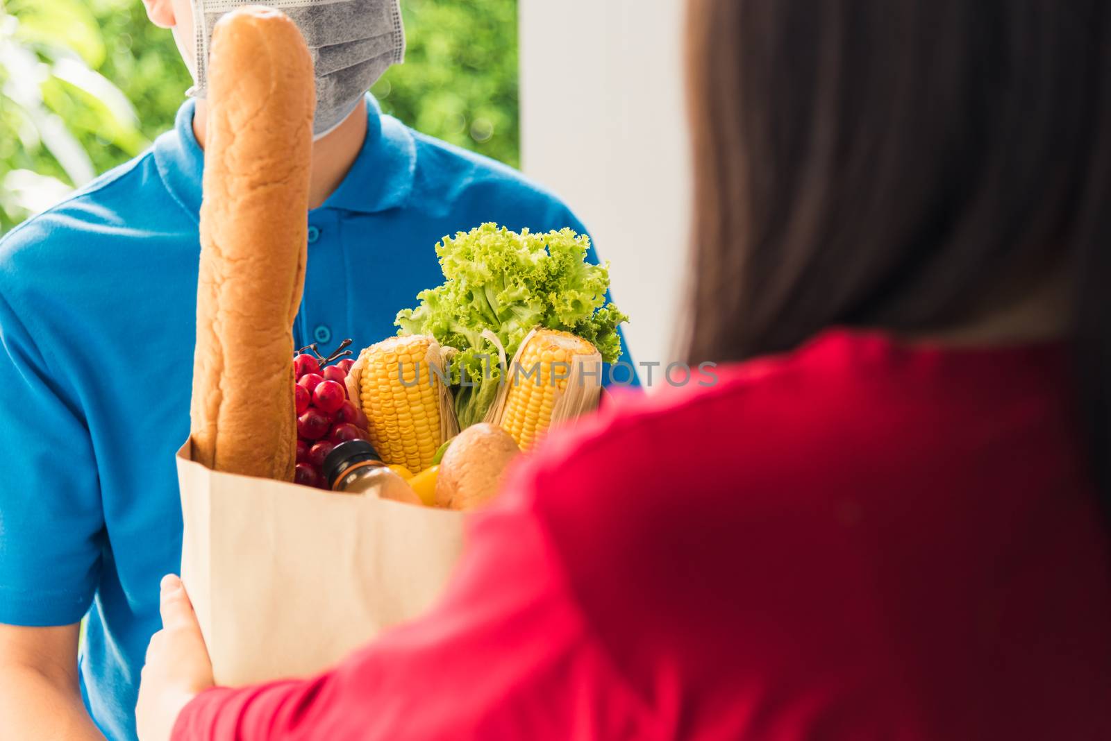 Delivery man wear protective face mask making grocery giving fre by Sorapop