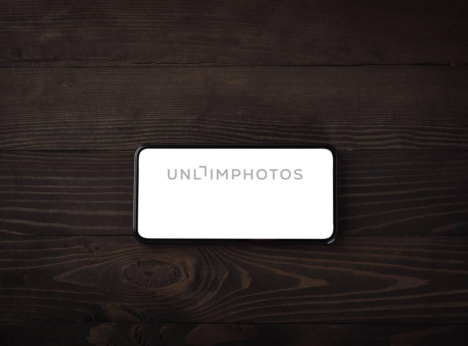 Close up top view of a modern smartphone on black wood table background vintage texture with copy space, mobile phone blank screen display