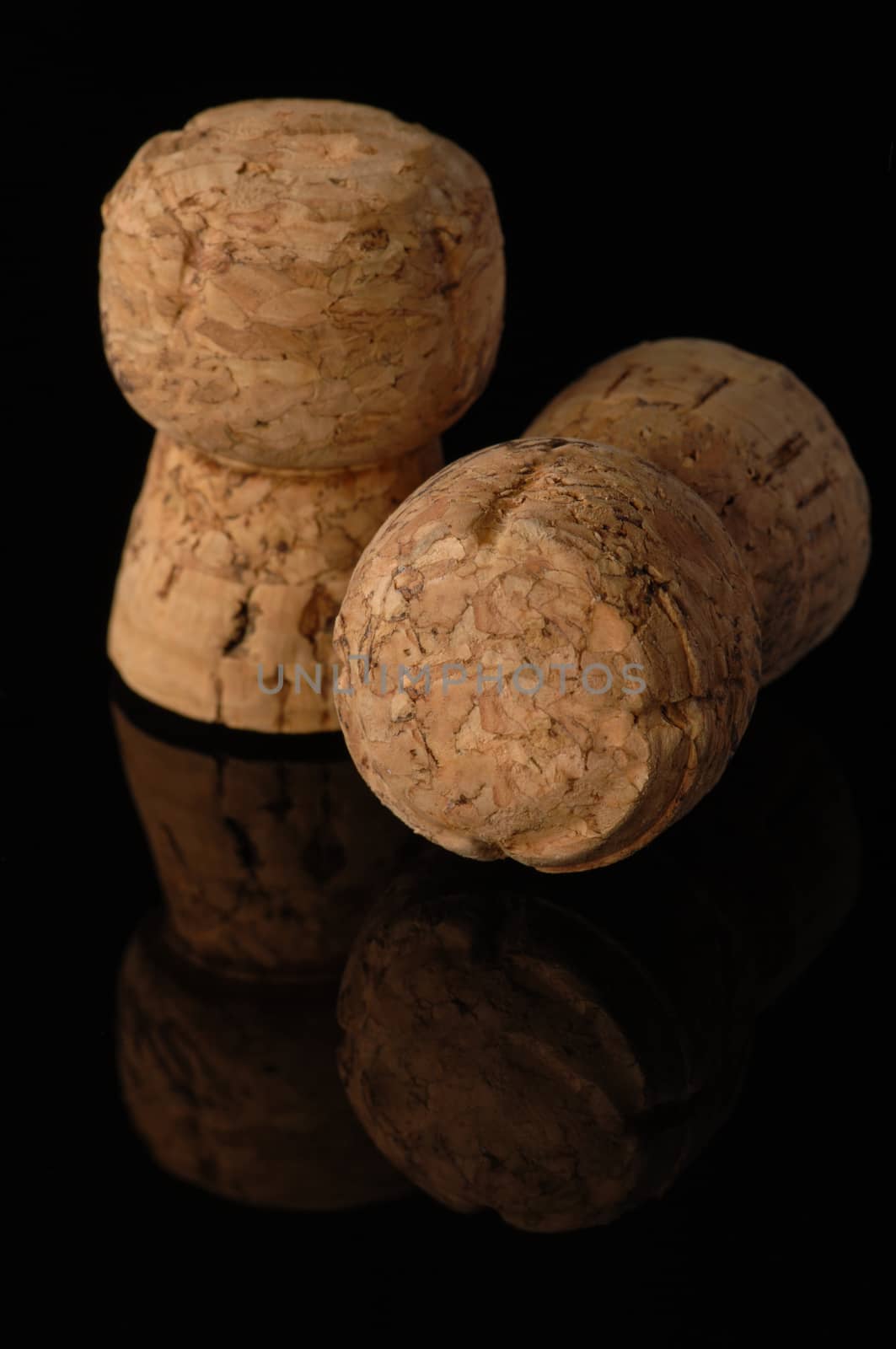 Two old wine corks on a black background with reflection