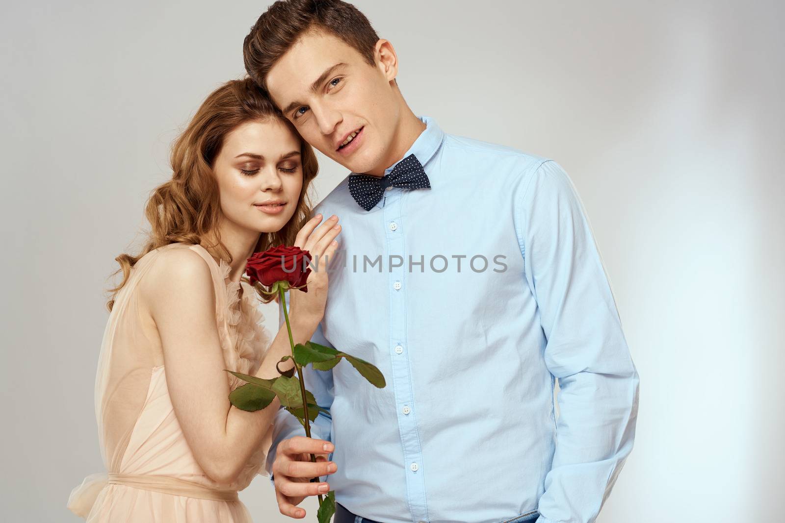 A loving young couple with a red rose in their hands on a light background romance by SHOTPRIME