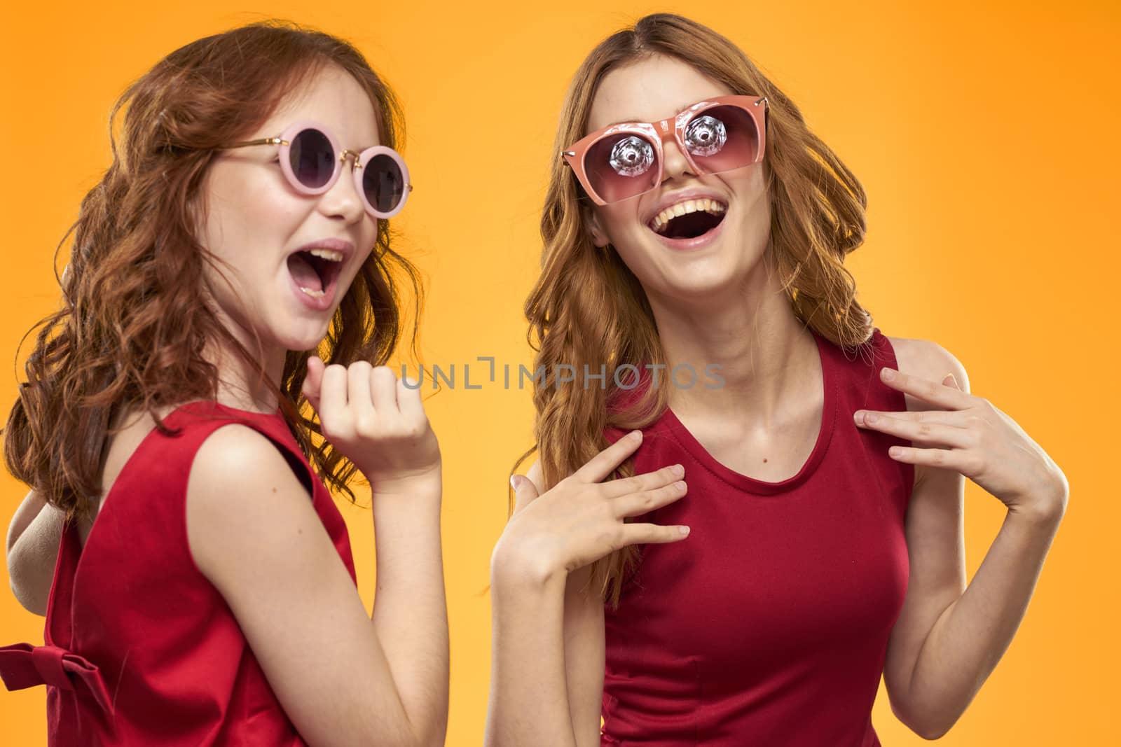 A red-haired girl and a beautiful woman on a yellow background in red dresses gesticulate with their hands and grimace by SHOTPRIME