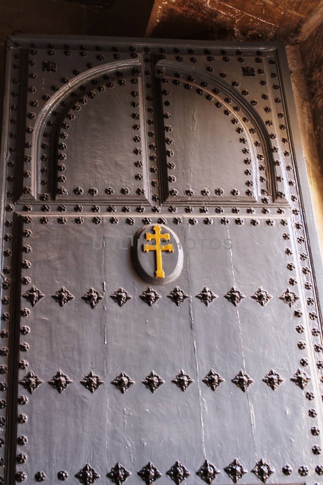 Old wooden gray door with wrought iron details in Caravaca de La Cruz, Spain