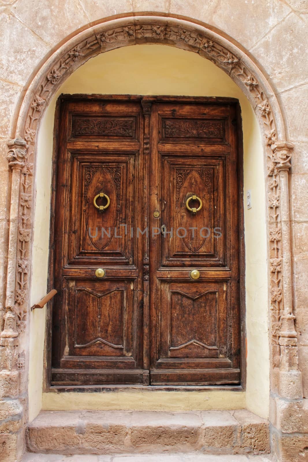 Old stone facade made of carved stone and vintage wooden door in a majestic house in Alcaraz, Albacete province, Spain.