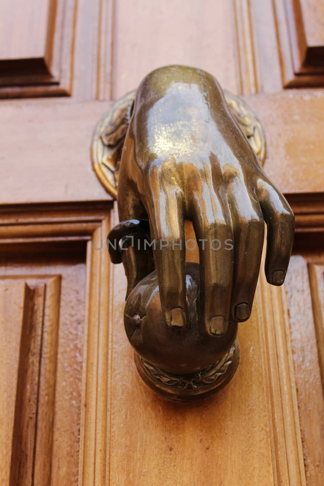 Golden doorknocker with hand shape on old brown wooden door in Alcaraz, Albacete, Spain