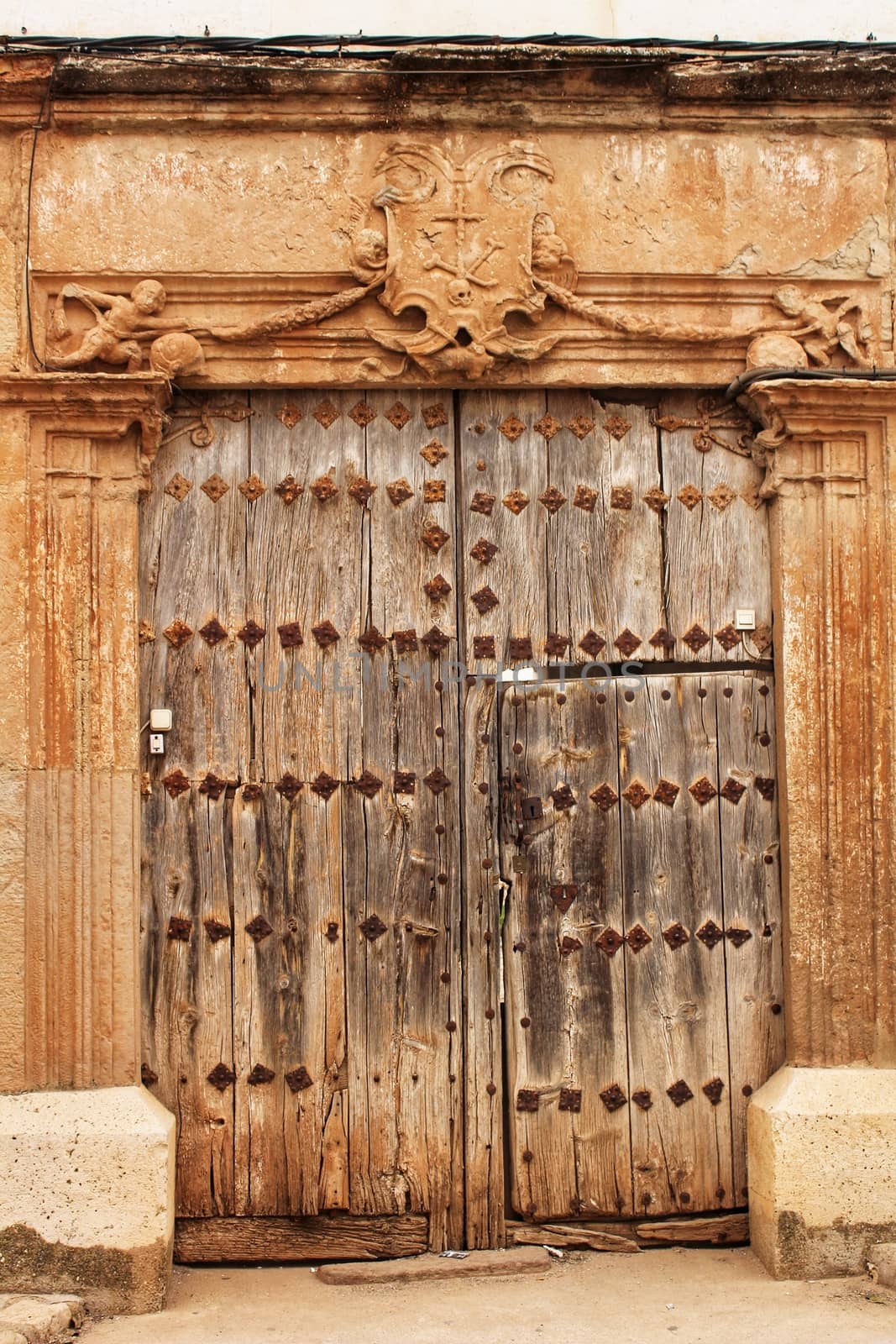 Old wooden door and coat of arms of the Holy Inquisition in a house in Villanueva de los Infantes, Castile-la Mancha, Spain
