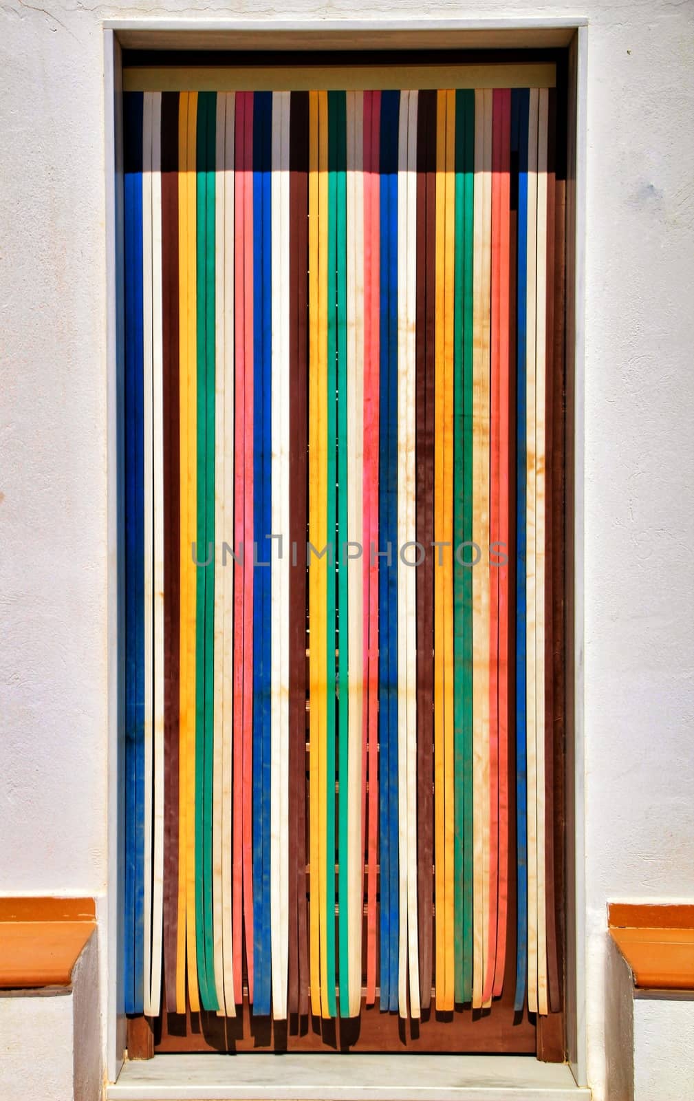 Colorful and striped curtain on door of village house by soniabonet