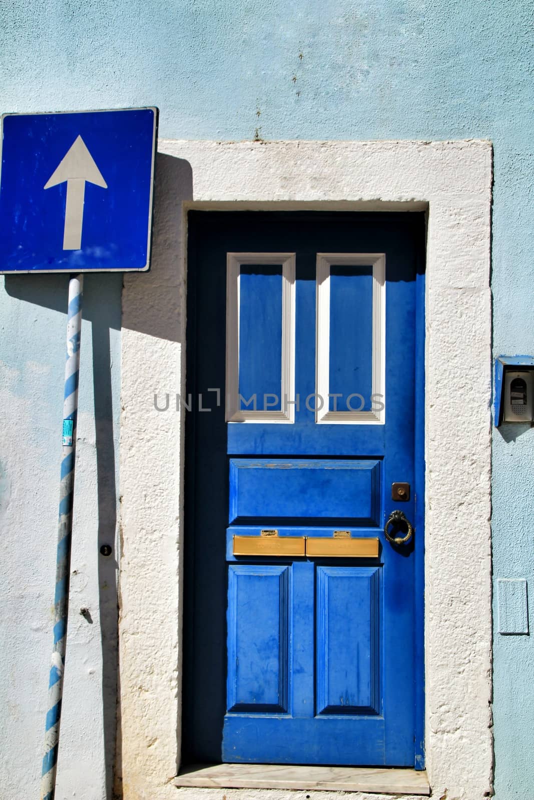 Old and colorful wooden door with iron details in Lisbon, Portugal. Traffic signal on the left hand side of the door.