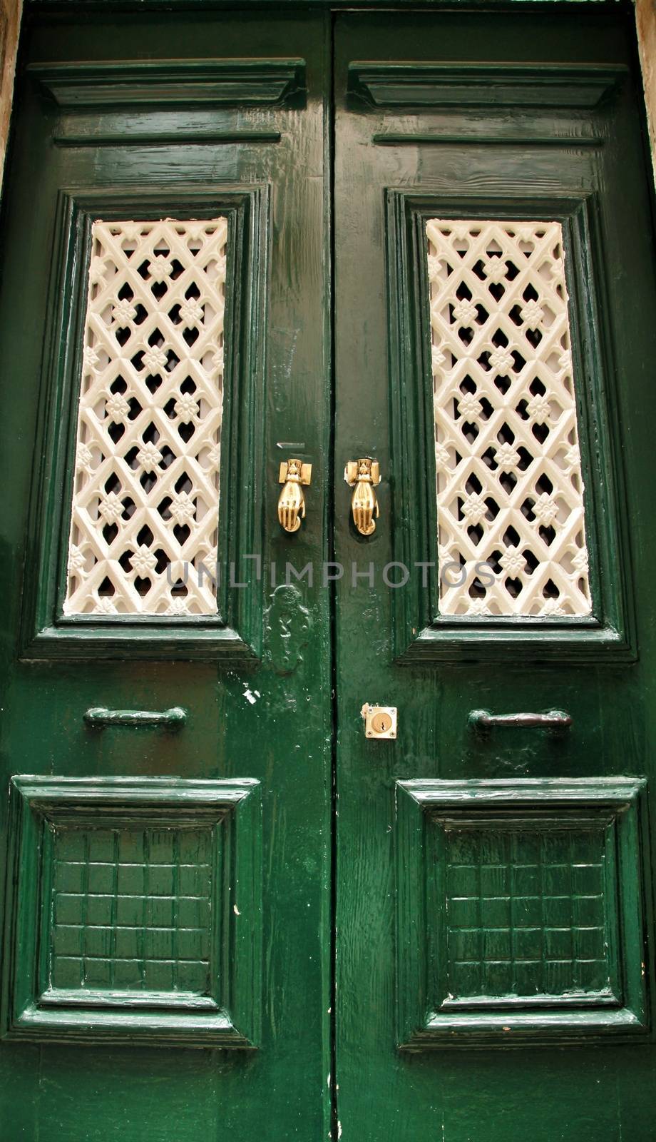 Door knockers with hand shape on green wooden door by soniabonet