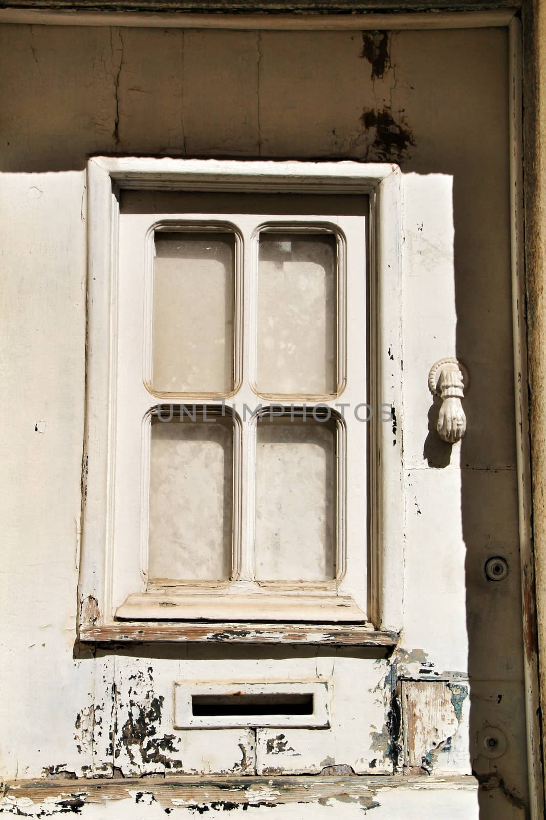 Doorknocker with hand shape on old white wooden door in Lisbon, Portugal