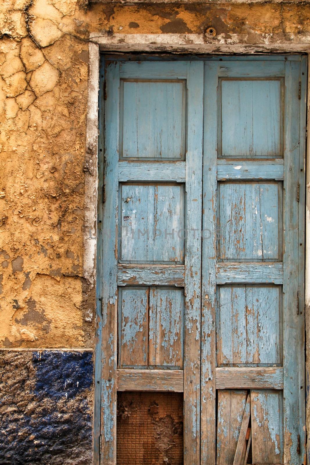 Old blue wooden door and damaged painted wall