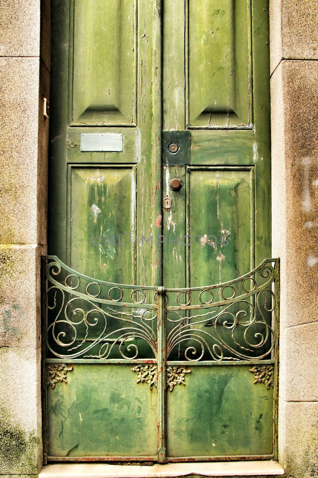 Old wooden green door with wrought iron fence in Porto, Portugal