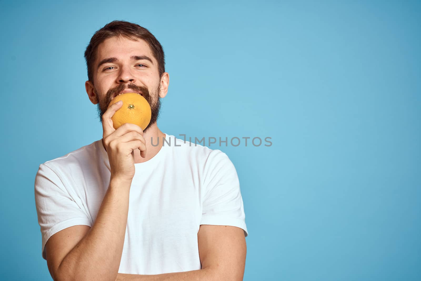 man with orange on blue background and cropped view Copy Space gesturing with hands by SHOTPRIME