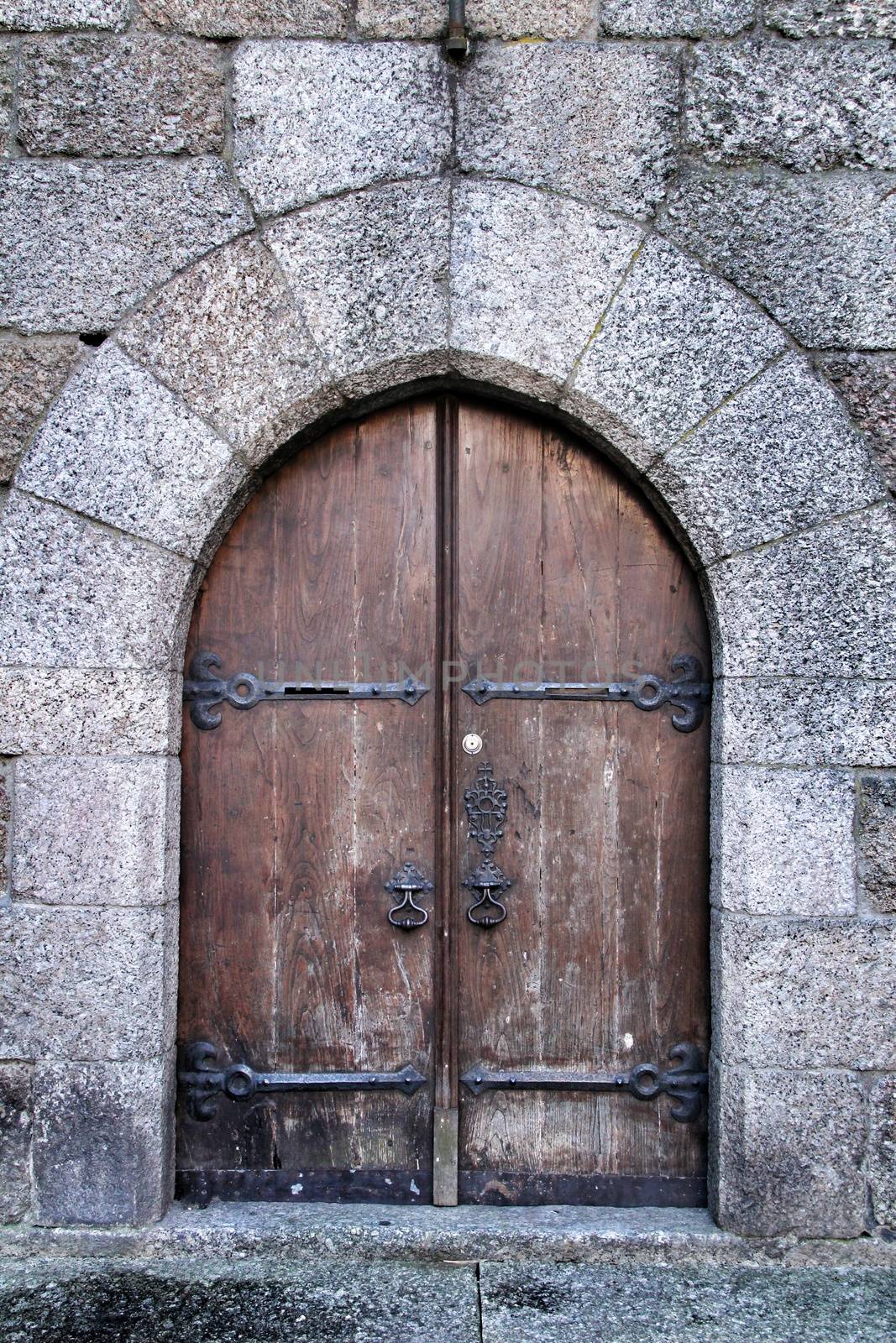 Old wooden brown door with wrought iron details by soniabonet