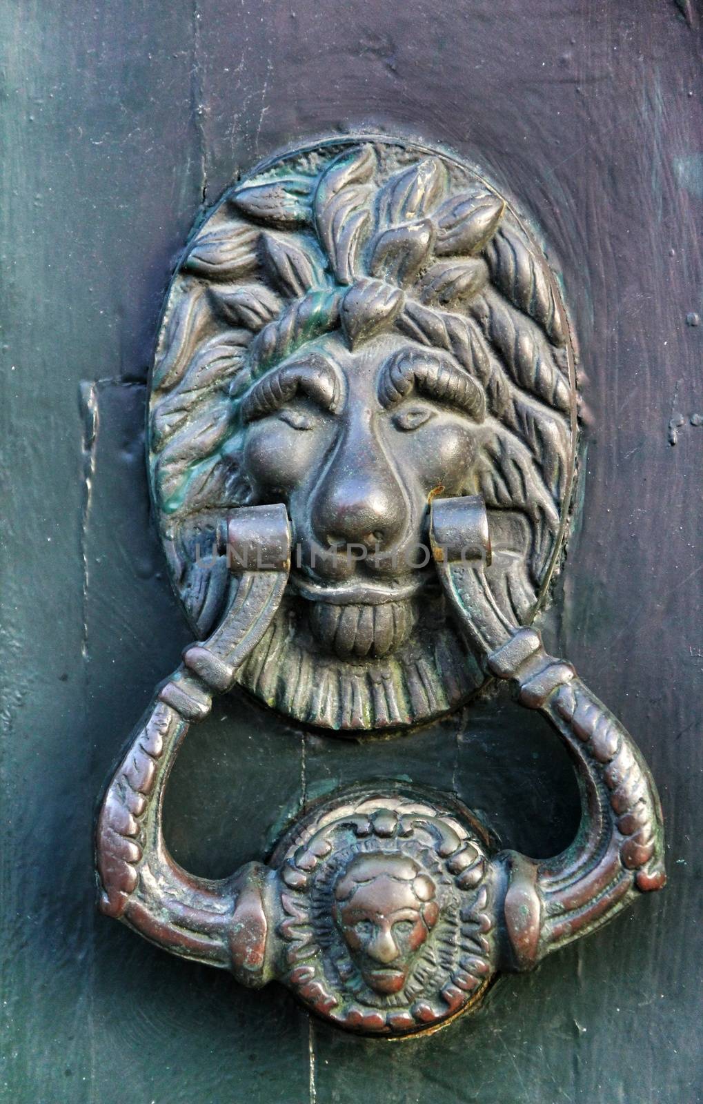 Vintage door knocker on green wooden door in Portugal