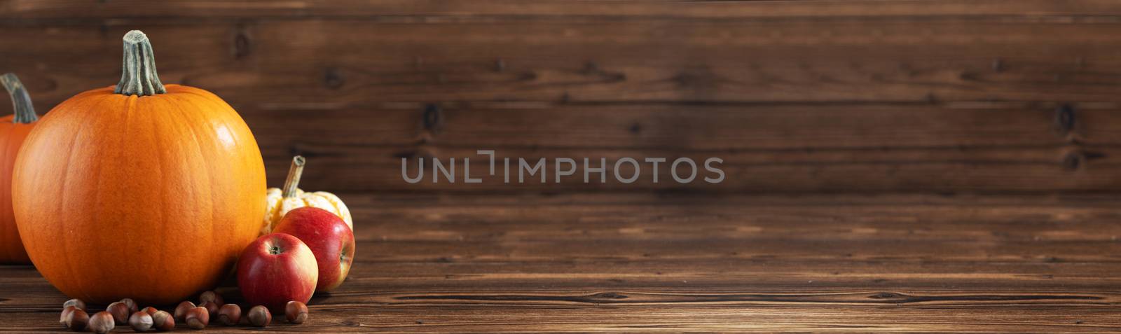 Wood background with pumpkin, apples and nuts. Copy space for text