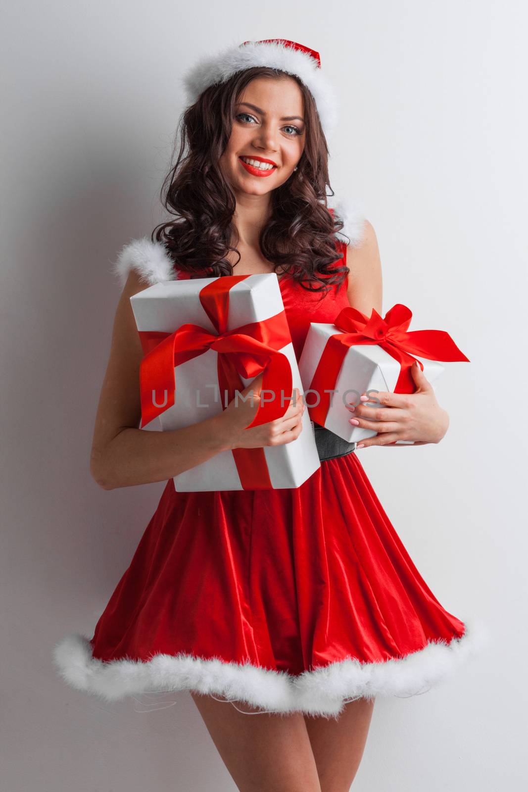 Smiling cute girl in red christmas outfit holding gift boxes