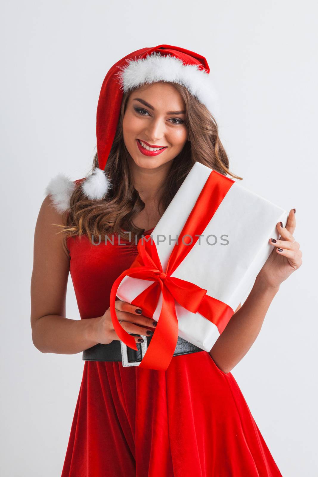 Smiling cute girl in red christmas outfit holding gift box on white background